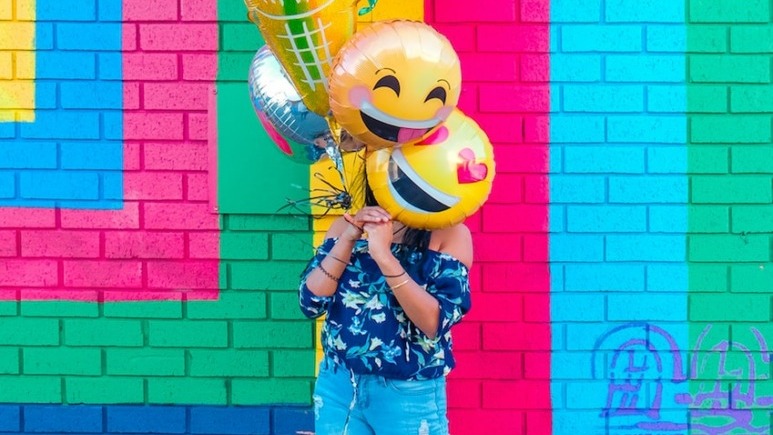 woman covering face with assorted ballons